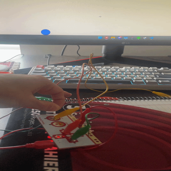 Testing a notebook as an interaction surface, attaching a clip to the spiral binding and touching the metal coil to see if it reliably triggers the Makey Makey.